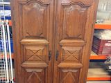 a large wooden armoire in a store with many other items