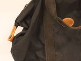 a black bag with a brown handle sitting on a white surface