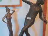 une statue représentant un homme tenant une lance et une femme tenant une épée