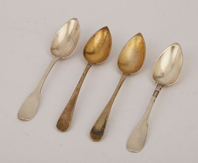 four silver spoons are lined up in a row on a white surface