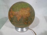 un globe posé sur un socle, sur une surface blanche