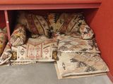 many pillows and pillows on the floor under a shelf