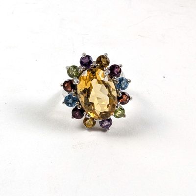 une bague ornée d'une pierre jaune entourée de pierres multicolores