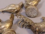 several silver metal birds are sitting on a white surface