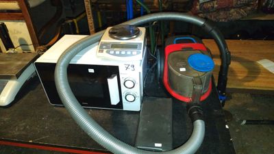 un micro-ondes et un aspirateur posés sur une table dans une pièce