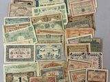 many different types of old paper money are displayed on a table