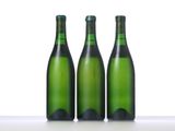 three green bottles of wine are lined up on a table