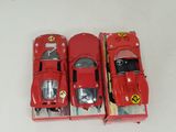 three red toy cars are lined up in a row on a white surface