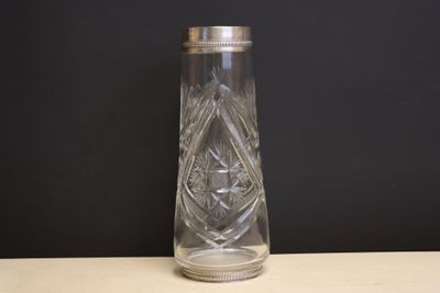 un vase en verre transparent avec un couvercle en argent posé sur une table