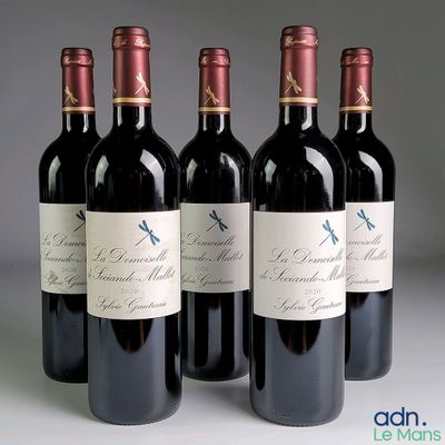 four bottles of red wine are lined up on a table