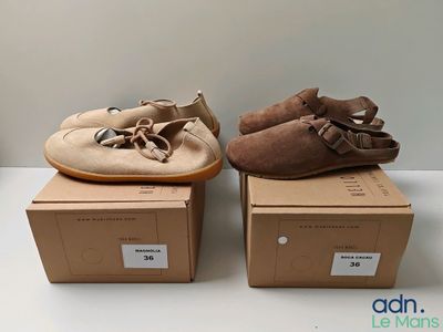 deux paires de chaussures de bébé posées sur des cartons, sur une table