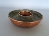 a small metal bowl with a copper rim on a white surface