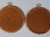 two gold - plated medallions, one with a brown leather surface and one with a gold - plate