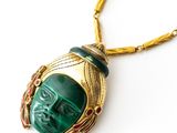 an image of a green and gold necklace with a face on it