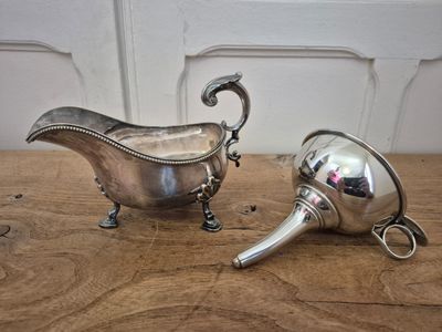 two silver plated items on a wooden table with a white wall