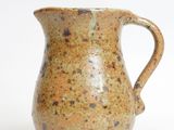 a brown pitcher with a handle on a white surface