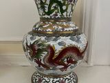 un vase orné d'un dragon, posé sur une étagère