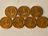 six souverains d'or empilés les uns sur les autres sur une surface blanche
