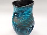 un vase bleu et noir posé sur une surface blanche