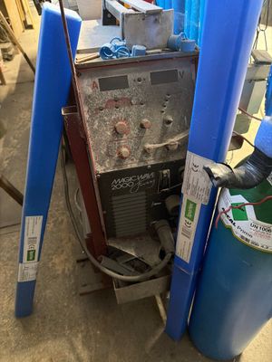une machine posée par terre à côté d'un réservoir bleu
