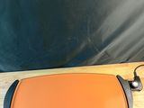 une poêle électrique orange et noire posée sur une table en bois