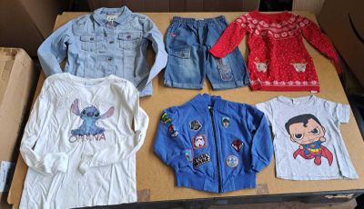 several children ' s clothing are displayed on a table in a cardboard box