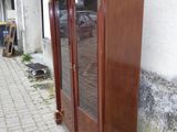 une armoire en bois avec une porte vitrée, située sur le côté d'un immeuble
