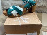 green and white sandals on a cardboard box with a brick wall in the background