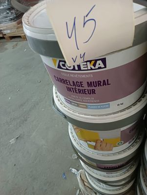 Plusieurs seaux de peinture sont empilés les uns sur les autres dans un entrepôt