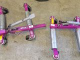a pink scooter laying on the floor next to other scooters