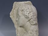 un gros plan sur la tête d'une femme sculptée, posée sur une surface blanche
