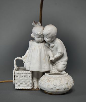 a white statue of two children with a basket and a lamp