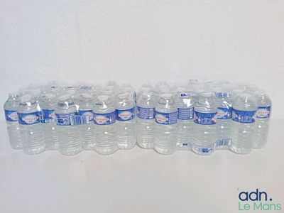 Plusieurs bouteilles d'eau sont alignées sur une table