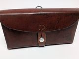 étui en cuir marron pour appareil photo posé sur une surface blanche