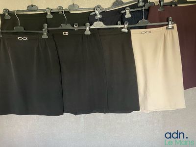 trois paires de pantalons suspendues à un portant dans une pièce
