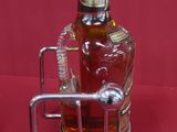 a bottle of liquor in a metal holder on a red background