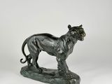 bronze statue of a lion on a rock on a white background