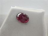 a close up of a red ruby stone on a white surface