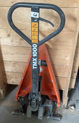 a fork lifter that is sitting next to a pile of wood
