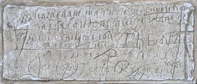 une vieille plaque en pierre portant une inscription, située devant un bâtiment