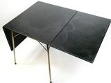 une image représentant une table pliante noire avec des pieds en métal