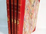 trois livres rouges sont empilés sur une surface blanche