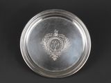 an antique silver plate with a crest on it on a black background
