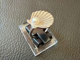 un anneau surmonté d'un coquillage, posé sur une surface en cuir