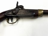 un vieux fusil exposé sur une surface blanche