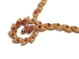 une image représentant un collier en or orné de pierres rouges et blanches, sur fond blanc