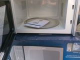 two microwaves stacked on top of each other on the ground