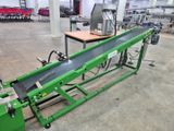 un tapis roulant vert dans une usine, avec une machine derrière
