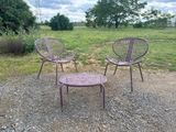 two purple chairs and a table sitting on a gravel road