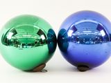 two shiny christmas balls sitting next to each other on a table
